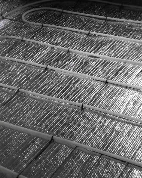Detalle del aislante reflectivo colocado bajo las tuberías de un piso radiante